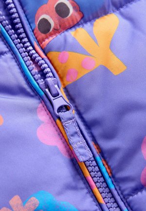 Violetti muovivetoketju sinisellä kankaalla, jossa on värikäs sarjakuvamainen mustekala sekä keltaisia ja vaaleanpunaisia kukkakuvioita.