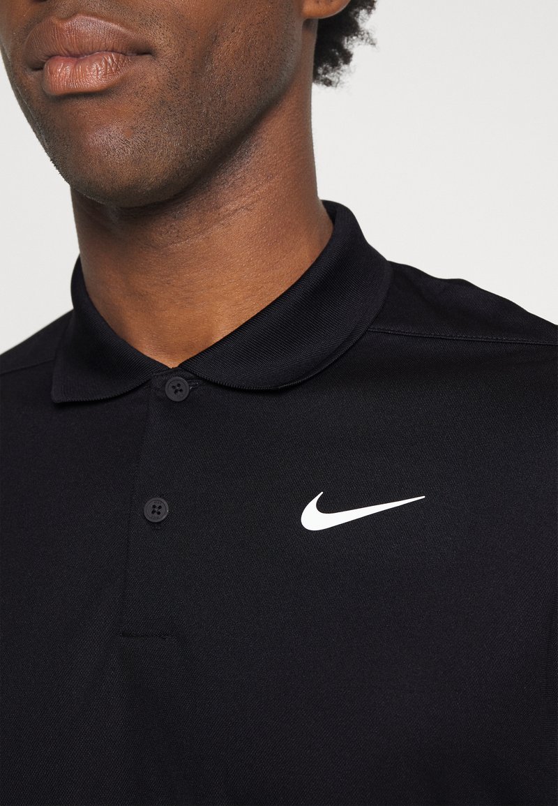 Polo shirt nero con colletto, due bottoni e logo Nike swoosh bianco sul lato sinistro del petto. Realizzato in tessuto testurizzato.