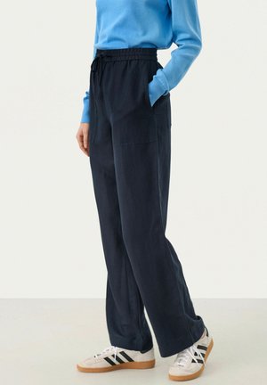 Navy blue wide-leg pants with an elastic waistband and side pockets, made from a soft material. Paired with white sneakers and a blue top.