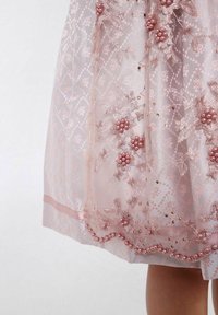 Robe en tulle rose ornée de broderies florales et d'accents en perles, avec une superposition transparente et un ourlet doublé, offrant un aspect texturé et délicat.