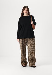 Zwarte longsleeve top, oversized fit; geprinte wijde leopard print broek in beige en bruin; zwarte platform sandalen; bruine crossbody tas.
