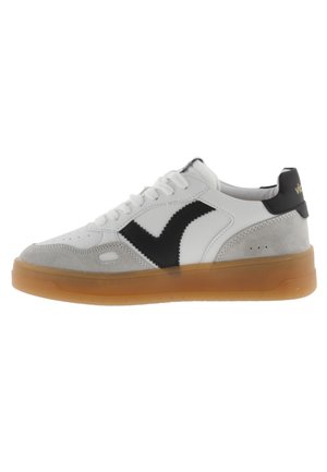 Sneaker bianca con accenti neri e grigi. Materiali in morbida pelle e suede. Punta arrotondata, chiusura con lacci e suola in gomma trasparente.