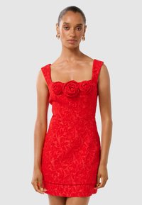 Robe rouge avec un décolleté carré, motif texturé floral, embellissements en rose tridimensionnels sur le buste, silhouette cintrée.