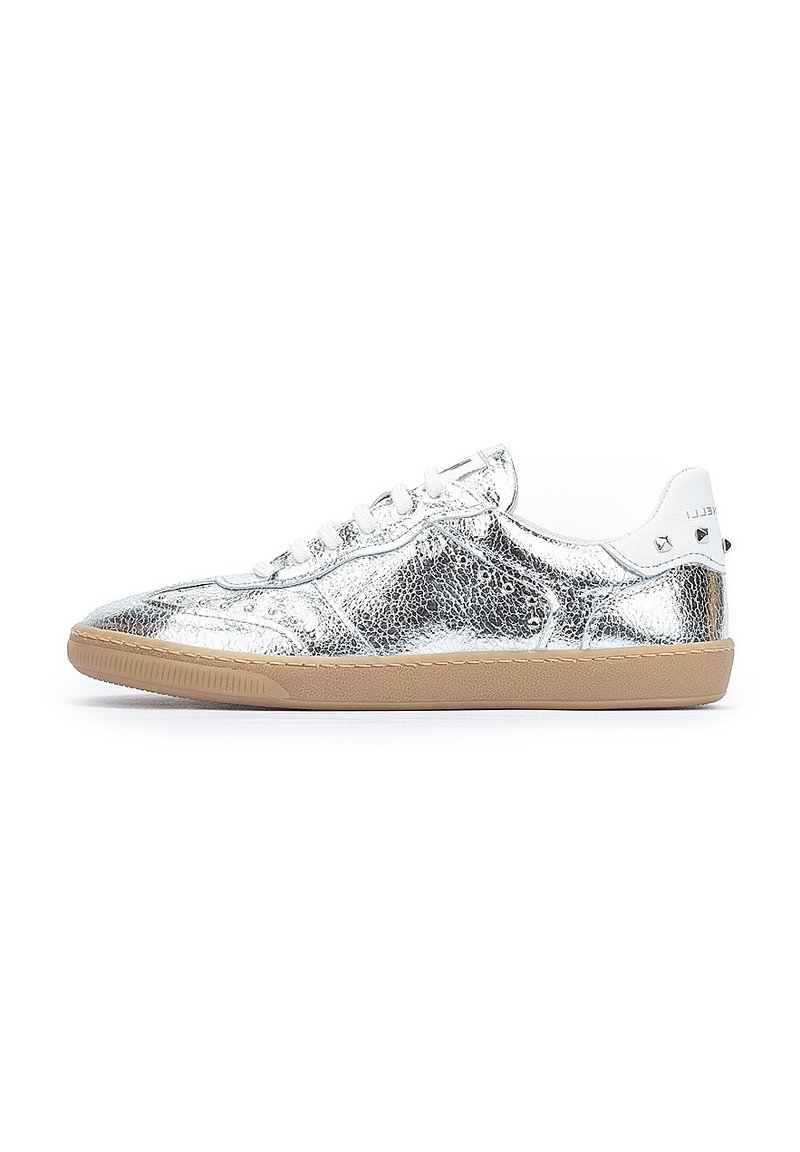 Zapatilla de cuero plateado con acabado texturizado, acentos blancos, cordones planos y suela de goma. Presenta tachuelas geométricas en el talón.