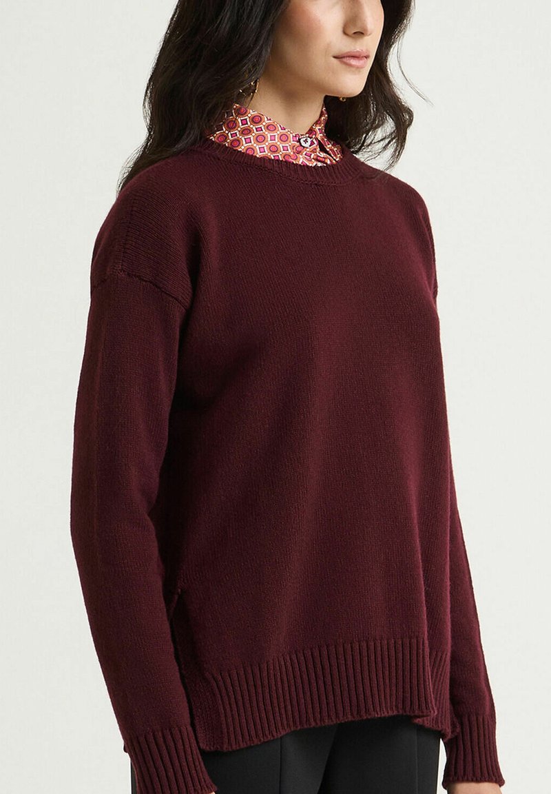Bordeauxroter Pullover mit klassischem Rundhalsausschnitt, geripptem Saum und Bündchen, leicht lockerer Passform und strukturierter Strickware.