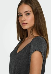 Sort V-hals top med korte ærmer med metallisk stribet mønster. Glat tekstur med en let glans, der følger kroppens form.