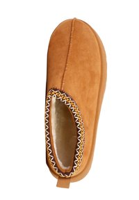 Tanfarvede ruskindstøfler med blødt indvendigt for, rund tå, fleksibel sål og dekorative gule og hvide syninger langs åbningen.
