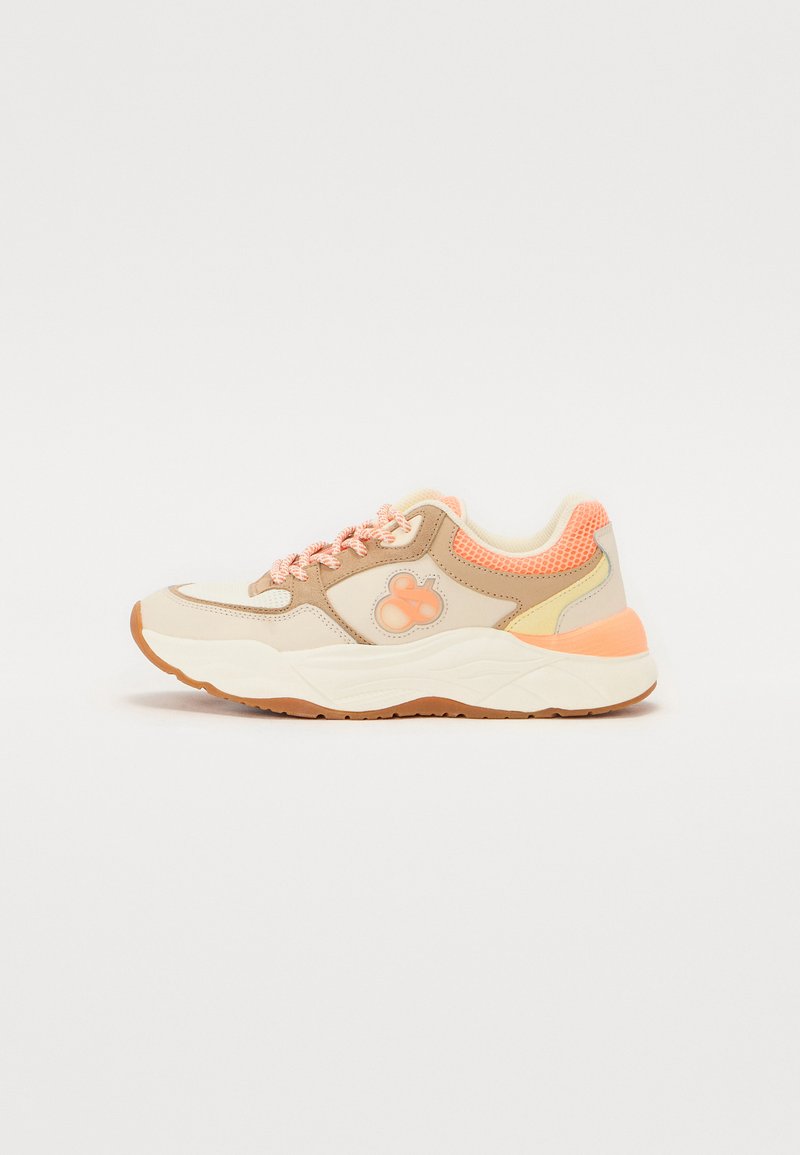 Sneaker with a beige upper, pink accents, mesh detailing, and textured sole. Features a rounded toe and contrasting lace design.