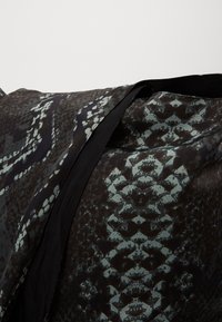 Zwarte stof met een slangenmotief in tinten groen en bruin, met een soepele textuur en een contrasterende zwarte bies langs de rand.