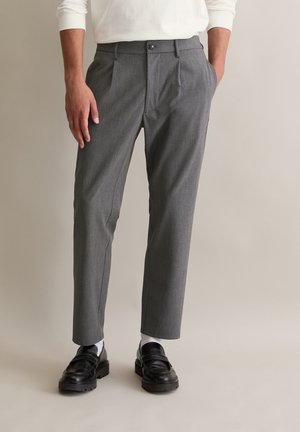 Gray checkered trousers made of a fabric blend, featuring a straight cut, pleated front, and a button closure, worn with black loafers.