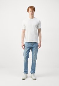 Hvit t-skjorte med korte ermer, lyseblå, rette jeans og hvite sneakers. Enkelt design med en avslappet passform; minimalistisk stil.