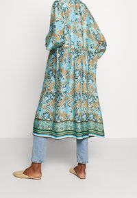 Lange bloemenkimono in beige en blauw, met een cinched taille, losse mouwen en een decoratieve zoom met horizontale strepen.