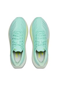 Mėtų žalios spalvos sportiniai batai su raišteliais, kvėpuojančiais tinklelio viršutiniais sluoksniais ir geltonais akcentais matomi iš viršaus ant balto fono.