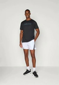 Svart kortermet treningsskjorte med "ENDLESS" logo, parret med hvite shorts med sideaksenter. Svart treningssko og hvite sokker.