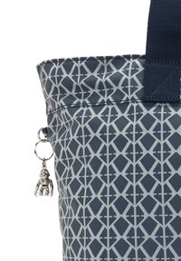 Marinblå mönstrad tote-väska med en geometrisk design i ljusgrått, utsmyckad med en silverberlock föreställande en figur som är fäst vid sidan.