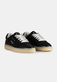 Baskets en cuir noir avec lacets blancs, bout rond et semelle en caoutchouc crème. Présente un logo sur le côté et sur la languette.