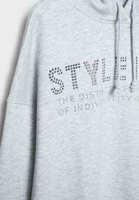 Szara bluza z kapturem wykonana z miękkiego materiału, ozdobiona kryształkami tworzącymi napis "STYLE" z przodu. Posiada kaptur ze sznurkiem i opadające ramiona.