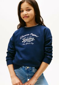 Sudadera de color azul marino con letras blancas, puños y dobladillo acanalados; presenta un diseño de logo con el texto "Tommy Hilfiger" y "Nueva York".