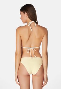 Lichtgele gehaakte bikini met verstelbare bandjes in de nek en op de rug. Hooghandige bikini-broekjes met een gestructureerde afwerking.