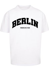 Witte katoenen t-shirt met zwarte "BERLIJN" tekst in vette boog en "MERCH•DE" eronder, met korte mouwen en een relaxed fit.