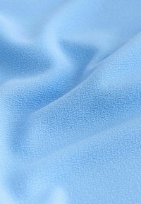Tissu doux bleu clair avec un motif de tricot fin et texturé montrant de légers plis et ombres.