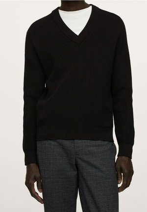 Zwarte v-hals trui van ribstof, met lange mouwen en een gestructureerd ontwerp. Draagt over een wit shirt met een rechte pasvorm.