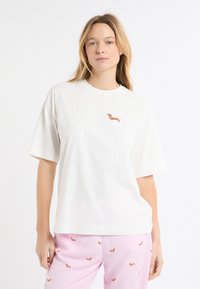 Maglietta bianca in cotone con un piccolo ricamo di un bassotto sul petto. Maniche corte e vestibilità comoda per maggiore comfort.