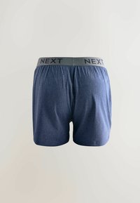 Modré boxerky z mäkkej látky. Majú sivý pás s nápisom "NEXT" v tmavých písmenách. Strih je voľný a pohodlný.