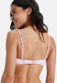 Różowy bikini górny z teksturą, z regulowanymi ramiączkami i zapięciem z tyłu. Posiada wzór w paski w delikatnych odcieniach różu i bieli.