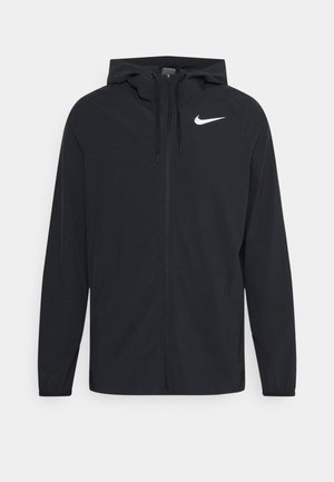Veste légère noire à capuche avec fermeture éclair intégrale devant et logo Nike blanc sur la poitrine gauche, poignets élastiques et poches avant.