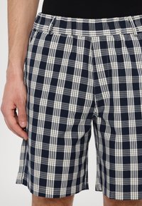 Marineblå og hvite rutete shorts med avslappet passform, med elastisk midje og sidespalter for ekstra komfort. Laget av bomull.
