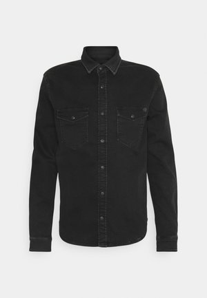 Chemise en denim noire à manches longues avec une patte de boutonnage à l'avant et deux poches poitrine à rabat, présentée sur un fond blanc.