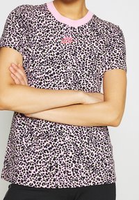 T-shirt med rosa leopardtryck tillverkad av mjukt material, med rund hals med rosa krage och en liten röd Nike-logotyp på bröstet.