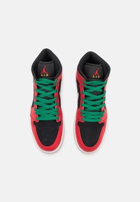 Pár vysokých tenisek s červenými a černými panely, zelenými tkaničkami, bílými podrážkami a červeným logem Jumpman Air na černých jazycích.