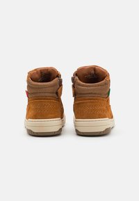 Bottines en suède marron avec une tige en maille, un col rembourré et une semelle en caoutchouc. Dotées de deux sangles latérales et d'accents colorés à l'arrière.