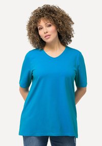 T-shirt turchese a scollo a V con maniche corte, realizzato in tessuto liscio, caratterizzato da una vestibilità rilassata e una leggera elasticità. Abbinato a jeans.