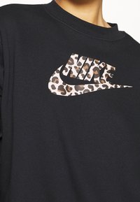 Zwarte sweater met een groot Nike-logo in een luipaardprintpatroon. Gemaakt van zachte stof met een ronde halslijn en een casual fit.
