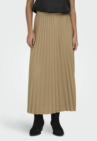 Falda maxi plisada color caqui hecha de una tela suave, con una cinturilla ancha, combinada con botas negras hasta el tobillo, presentada sobre un fondo claro.