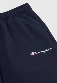 Navyblaue Sweatpants aus weichem Stoff verfügen über einen elastischen Bund und ein kleines weißes Champion-Logo mit roten und weißen Akzenten.