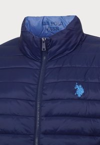 Mørkeblå pufferjakke har høj krave, lynlåslukning, vandret quiltet design og lys blå broderet logo på brystet.