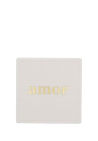 Vit fyrkantig sammetssmyckesask med guldtexten "amor" centrerad ovanpå.