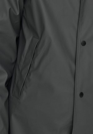 Gray waterproof jacket with a smooth texture, side pocket, and button closure. Features a sleek design with minimalistic details.