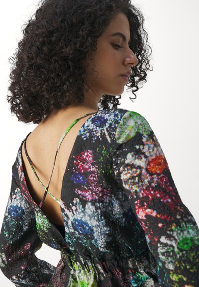 Robe florale multicolore avec une base noire, dotée de manches longues, d'un dos en V profond et de fines bretelles. Le tissu a une surface texturée.