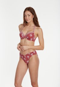 Červený bikiny set s vzorovaným topom so štruktúrovaným dizajnom a nastaviteľnými ramienkami, skombinovaný s nízko posadenými spodnými časťami, obe majú biele motívy paliem.