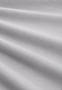 Tissu en coton blanc avec une texture lisse, présentant un léger éclat et un subtil motif de tissage diagonal, disposé en douces plis.