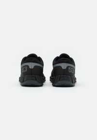 Pár černých a šedých sportovních bot zobrazených ze zadní strany s textem "03" a "Wave Ibuki GTX" v oblasti paty.