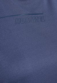 Niebieska tkanina teksturowana z prążkowanym wzorem, z subtelnym wytłoczonym logo "HUMMEL" w pasującym odcieniu.