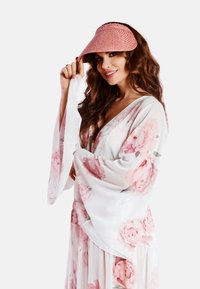 Sukienka w kwiatowy wzór z długimi, zwiewnymi rękawami z lekkiego materiału, dopełniona różowym kapeluszem z słomy. Półprzezroczysta tekstura.