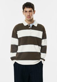 Długi rękaw polo w ciemnobrązowe i białe paski z delikatnym niebieskim akcentem, z trzema guzikami przy kołnierzyku i ściągaczami przy rękawach.