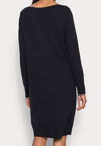 Marinblå långärmad klänning i mjukt tyg, med vid halsringning, sidoflikar och kontrasterande röda detaljer på ärmarna.